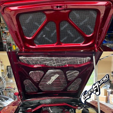 Red car hood lifted, revealing the engine compartment and interior details.