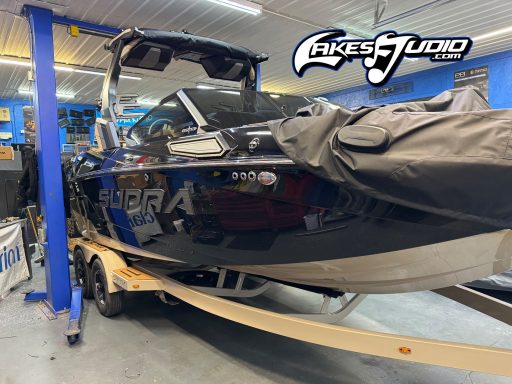 Black and blue ski boat on a trailer, inside a garage with tools and equipment visible.
