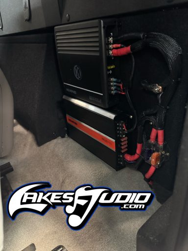 Car audio equipment mounted on a panel, featuring amplifiers and wiring.