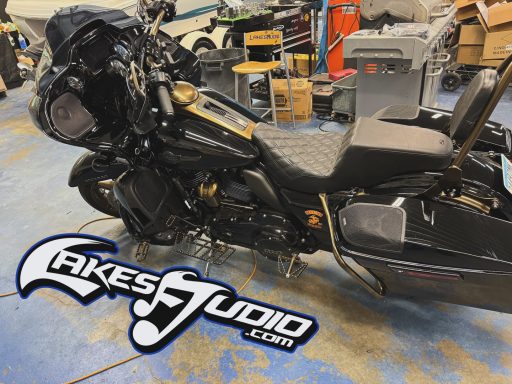 A black motorcycle parked in a workshop with tools and equipment in the background.