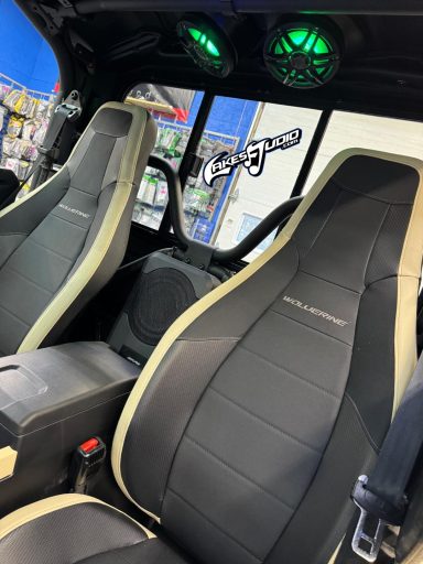 Black and beige car seats with green ambient lighting in a modified vehicle interior.