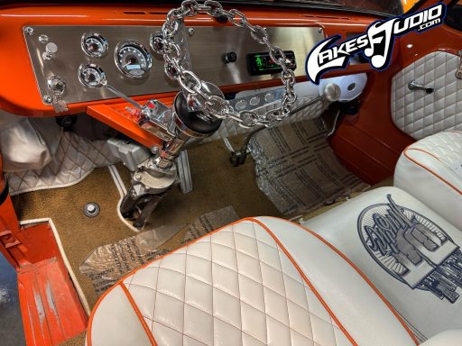Interior of a vintage car featuring orange accents, chrome details, and distinctive seat upholstery.