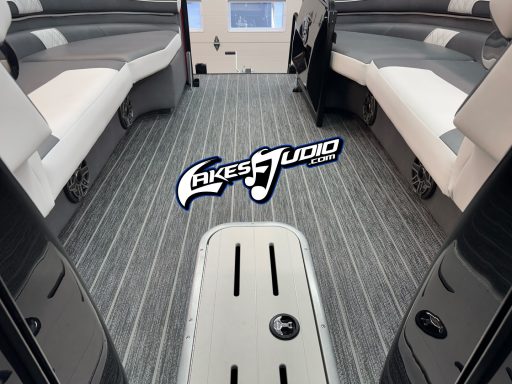 Interior of a boat featuring cushioned seating and a patterned floor, with a logo in the center.