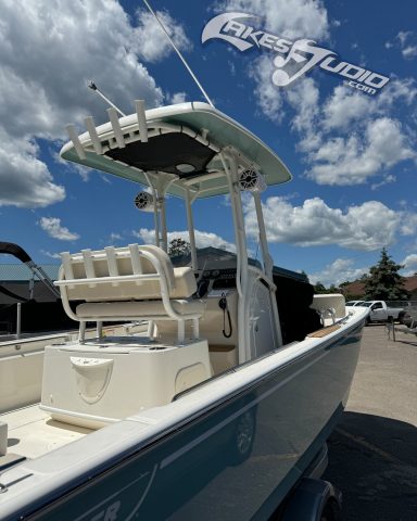 A light blue boat docked, featuring a T-top and seating at the helm, under a cloudy sky.
