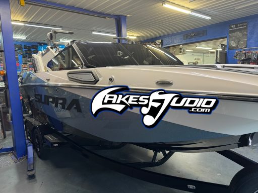 A sleek boat parked in a workshop with "ULTRA" and "Lakes Audio" branding visible.