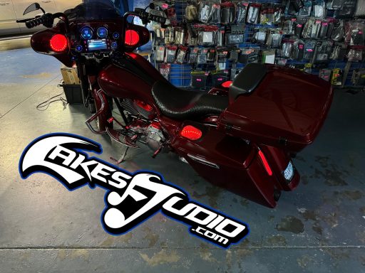 A red motorcycle parked in a workshop with various tools and parts visible in the background.