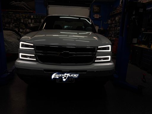 Front view of a silver Chevrolet truck in a dimly lit garage.